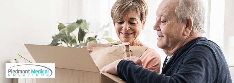 Older man and woman opening a cardboard box together