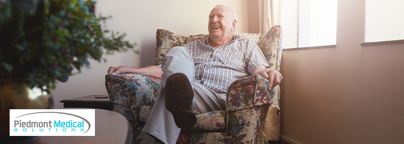 Smiling elderly man sitting comfortably in floral armchair 