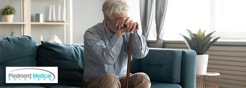 Older gentlemen resting his head on his cane while sitting on the couch